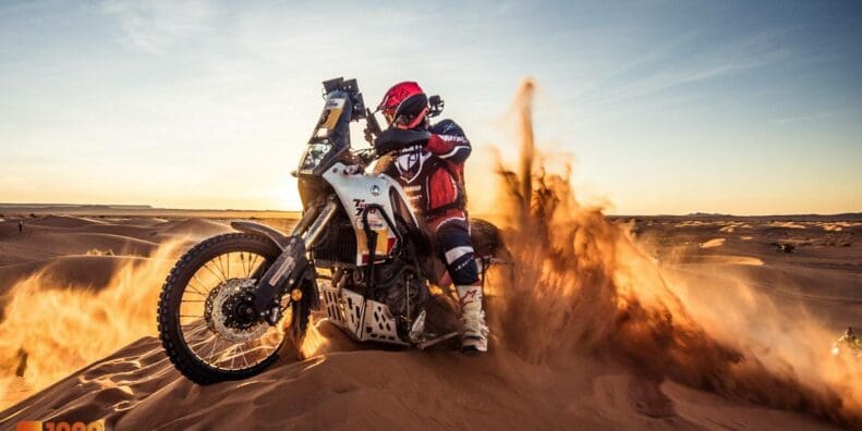 A view of a racer in the 1000 Dunas raid traversing desert dunes on a sunny day