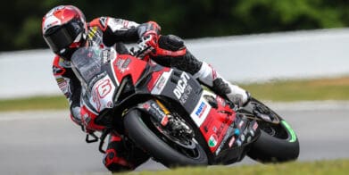 A front view of Loris Baz at the MotoAmerica Superbike Championship, leaning into a turn.