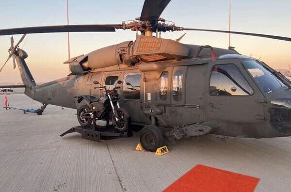 a military helicopter featuring a side-mounted electric motorcycle in prototype for stealth missions