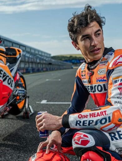 Marc Marquez with his Honda racebikje in the background. Media sourced from The Guardian.