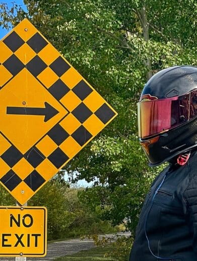 Author wearing Icon Airframe Pro Carbon Helmet and standing next to road sign