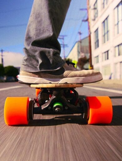 Close up of man riding electric skateboard through town