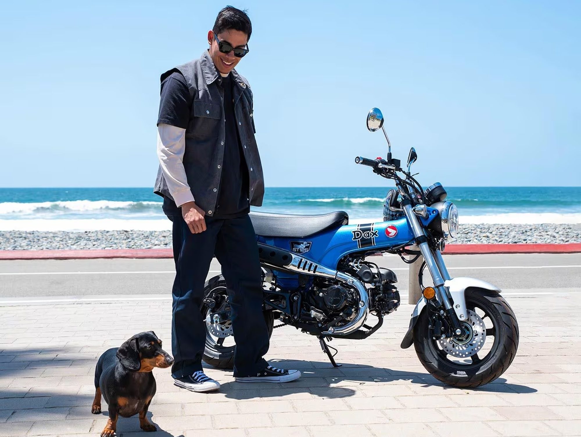 A Honda Dax 125 next to a man and a daschund.