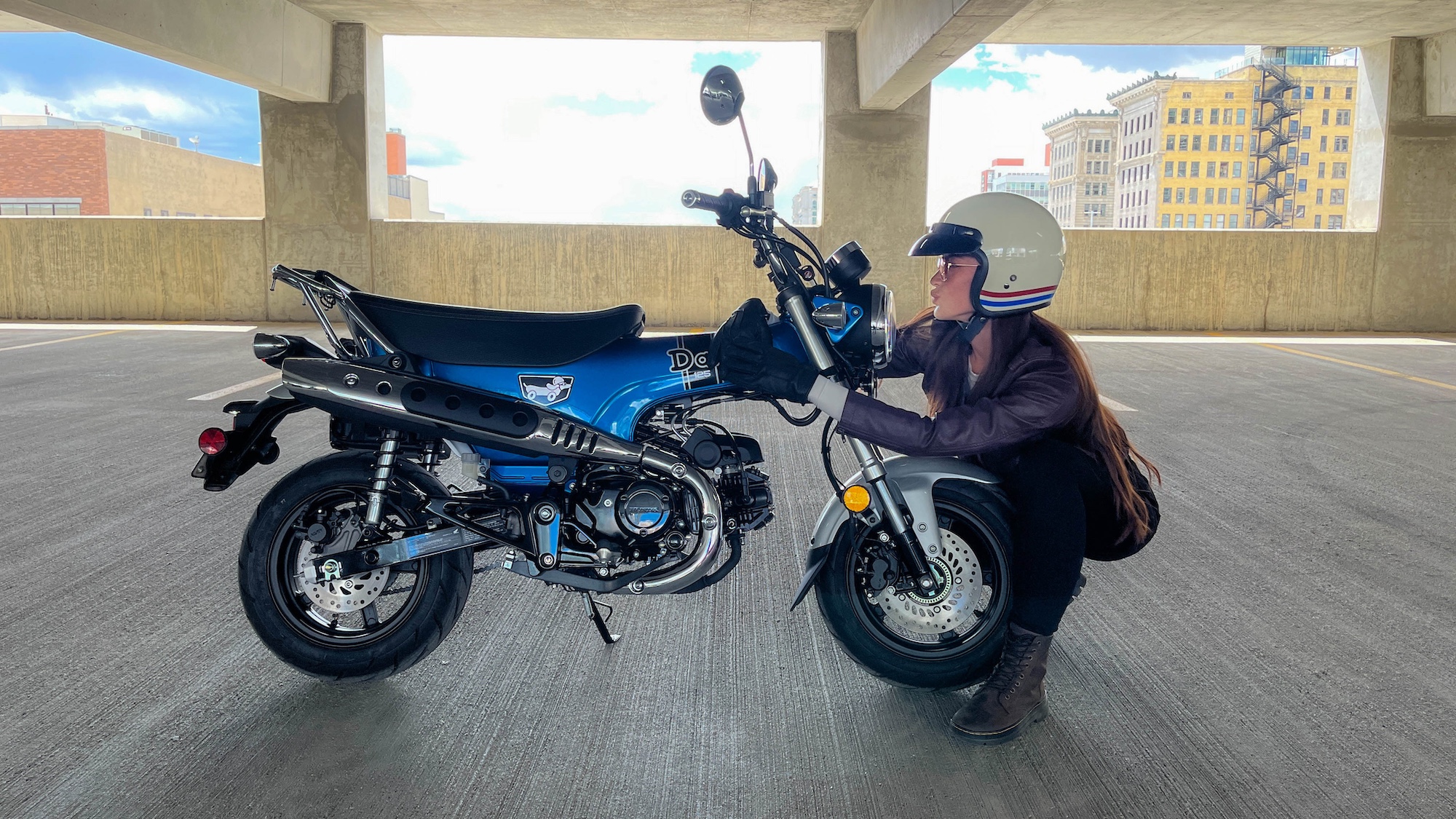 A view of Honda's Dax 125 beside a woman.