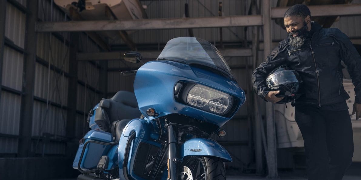 A front view of a man standing next to a Harley-Davidson's 2024 Road Glide Limited.