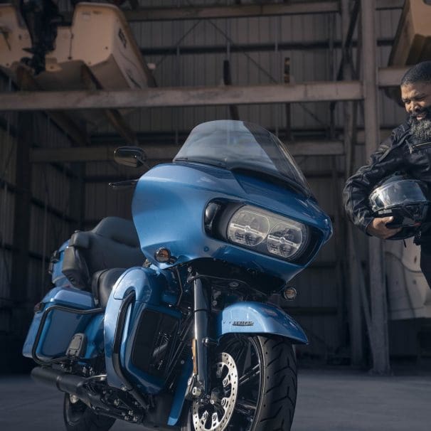 A front view of a man standing next to a Harley-Davidson's 2024 Road Glide Limited.