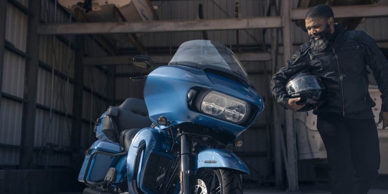 A front view of a man standing next to a Harley-Davidson's 2024 Road Glide Limited.